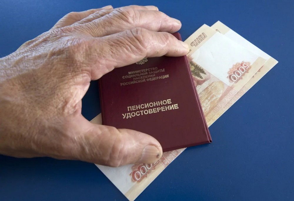 Рука на купюрах и пенсионном удостоверении